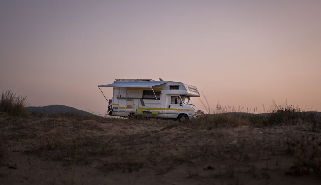 A serene view of an RV parked amidst nature during sunset, capturing a travel adventure.